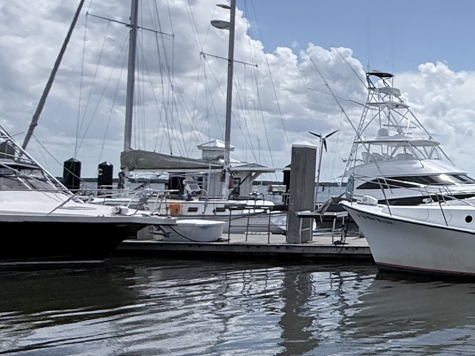 Sailboats and a sportfishing yacht docked at a marina on calm water under a partly cloudy sky in Fernandina Beach, Florida