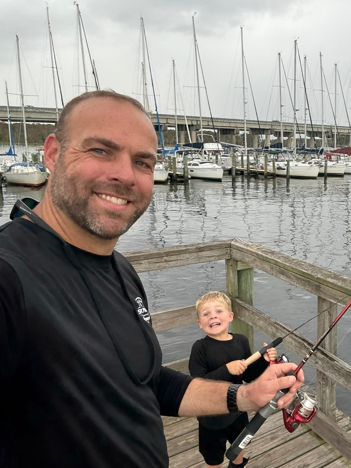 Tim Sherman on a dock with a child holding a fishing rod